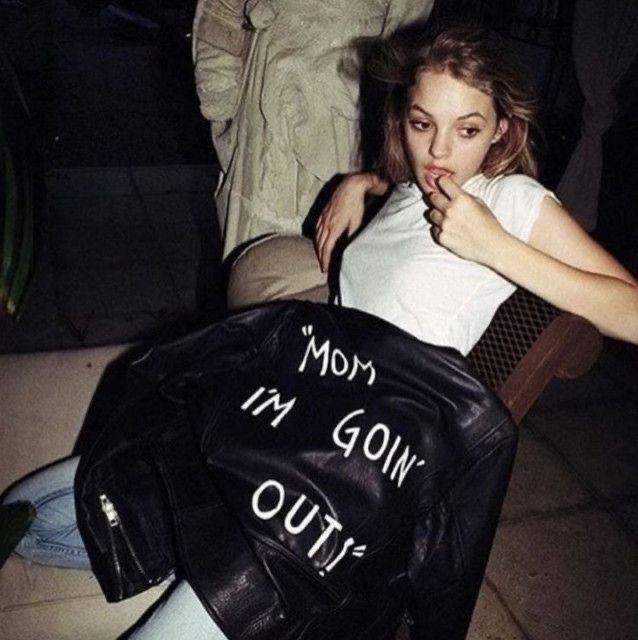 a woman sitting in a chair with a bag on her lap and another person standing behind her