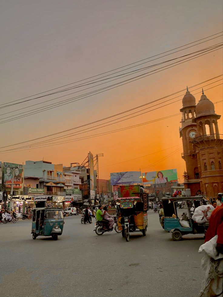 the sun is setting over a busy street with cars and scooters driving down it