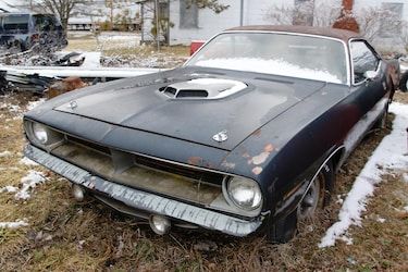 an old car sitting in the grass with snow on it's hood and windshield