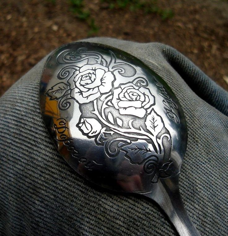 a silver spoon with flowers on it sitting in someone's lapel pocket,