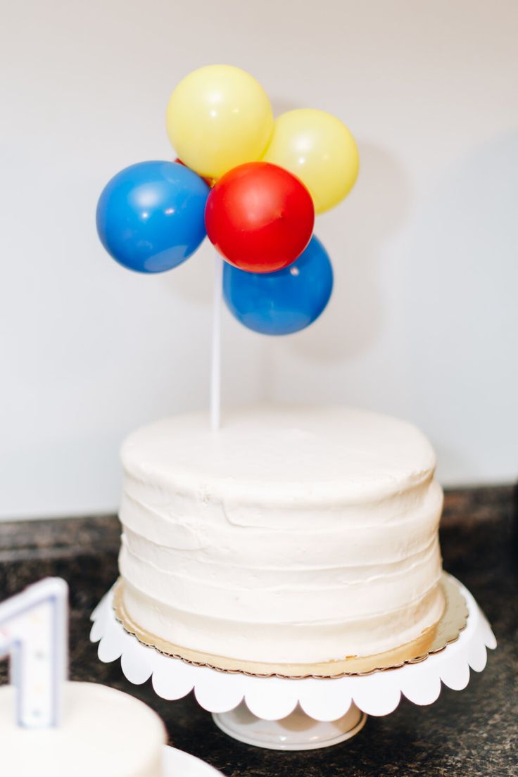 a white cake topped with balloons on top of a table