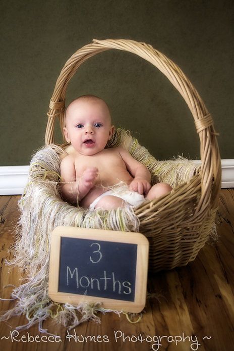 a baby sitting in a basket with a chalkboard