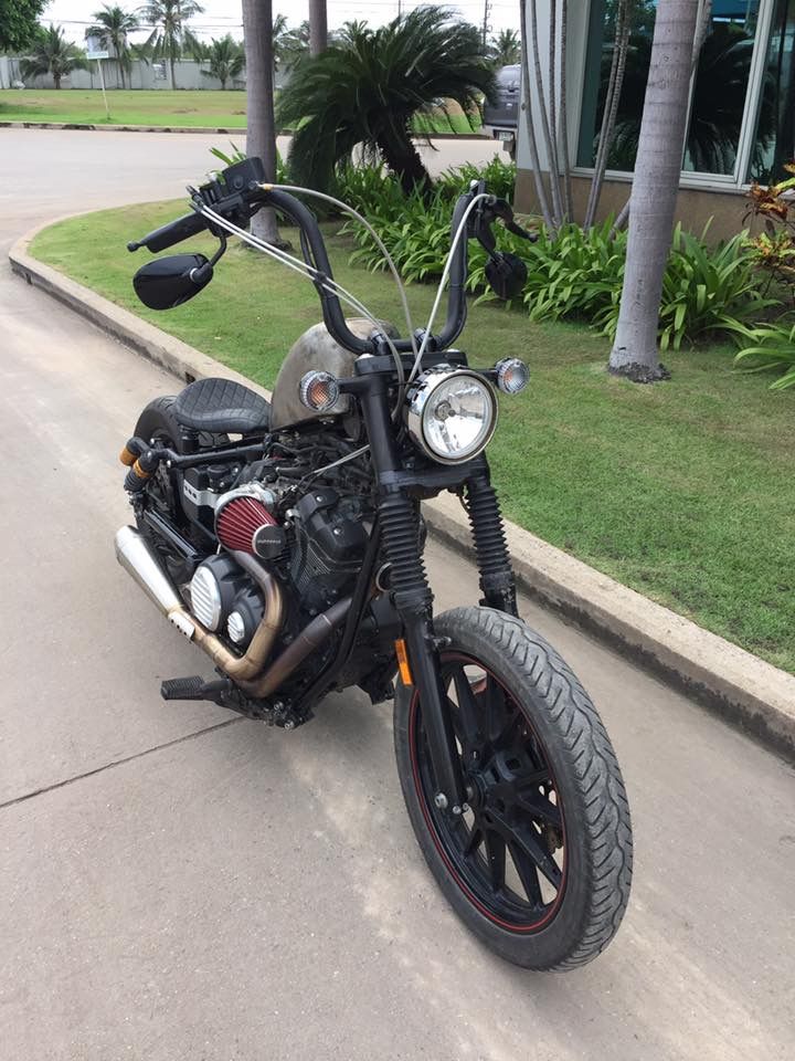 the motorcycle is parked on the side of the road next to the grass and palm trees