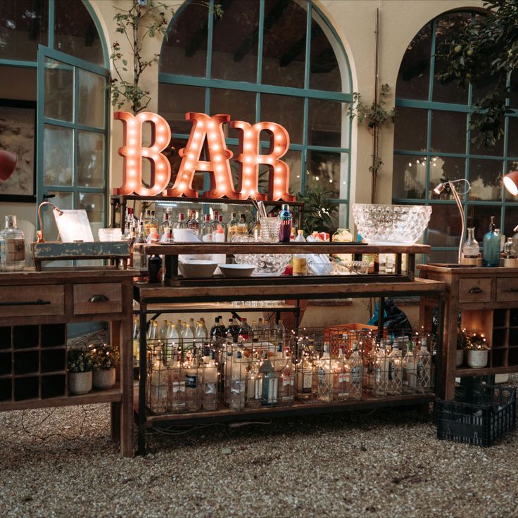 an outdoor bar with lighted letters and bottles