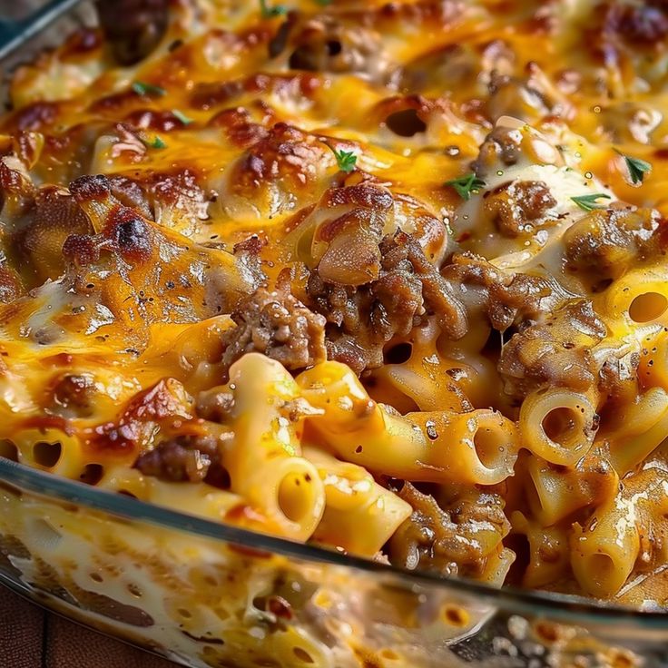 a casserole dish with meat, cheese and noodles in it on a wooden table