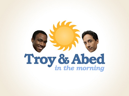 two men are smiling in front of the logo for troy and abed in the morning