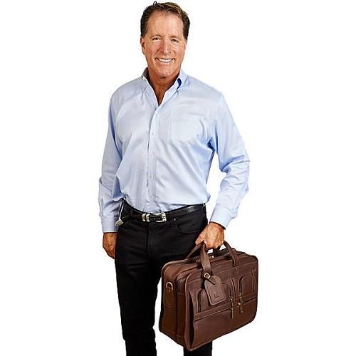 a man standing with his hands in his pockets and holding a brown briefcase on his hip