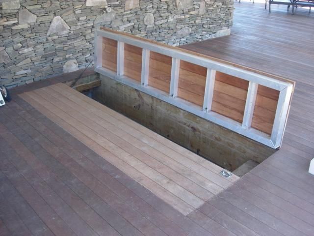 a wooden bench sitting on top of a hard wood floor next to a stone wall