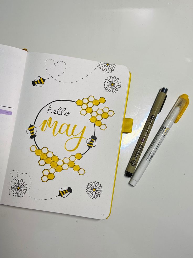 an open notebook with the words hello may written on it and two pens next to it