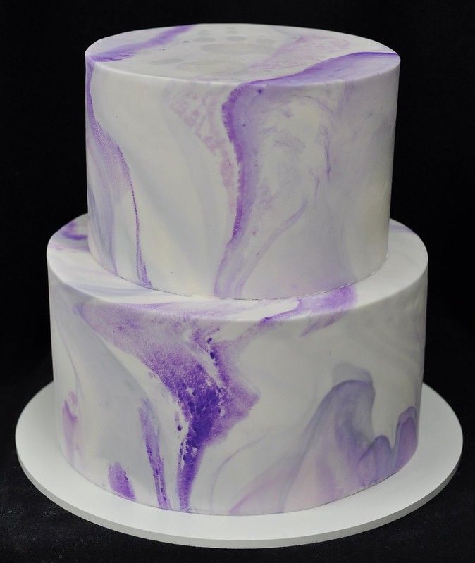 a three tiered cake with purple and white marbled icing on it's sides