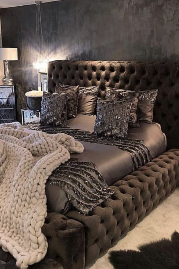 a large bed with lots of pillows and blankets on it's headboard in a bedroom