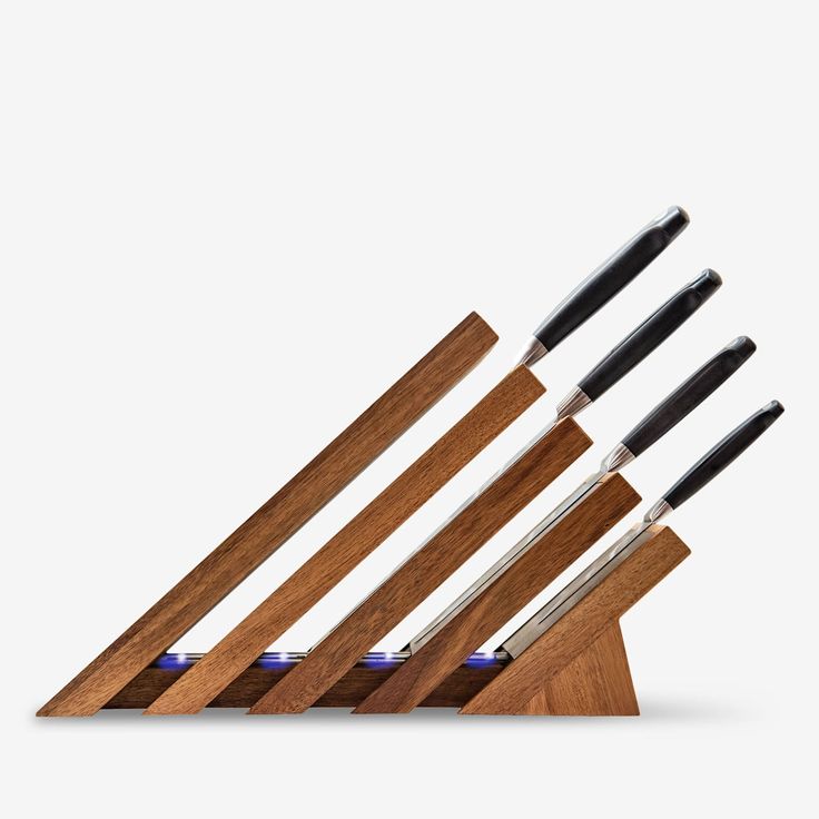 a set of four knives sitting on top of a wooden stand with black handles and blue tips