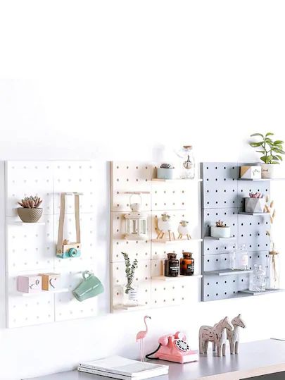 a white desk topped with lots of shelves filled with books and toys next to a wall mounted pegboard