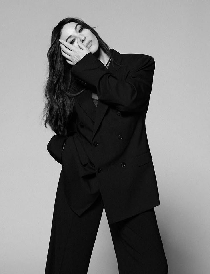 black and white photo of woman in suit posing with hands on her face as if she is covering her eyes