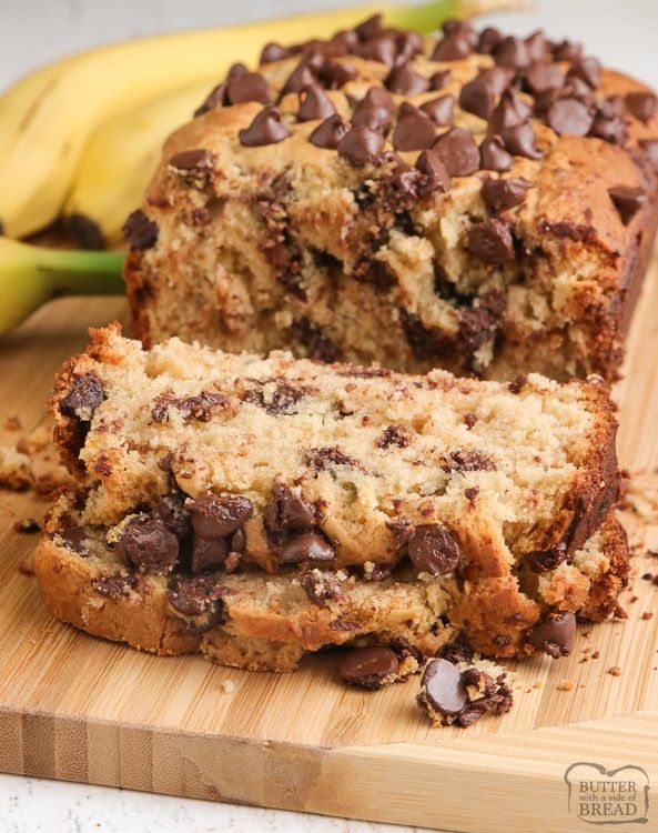 a loaf of chocolate chip banana bread on a cutting board next to some ripe bananas