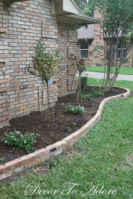 a brick wall and flower bed in front of a house