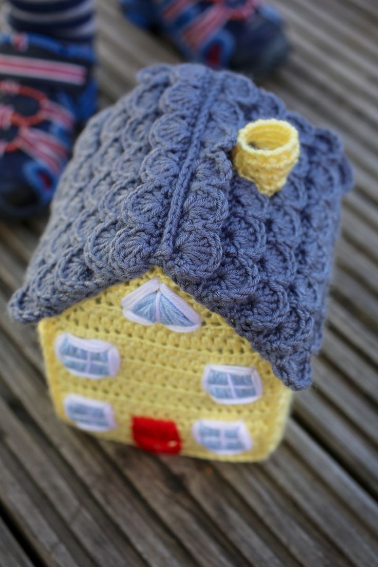 two small knitted houses sitting on top of a wooden table