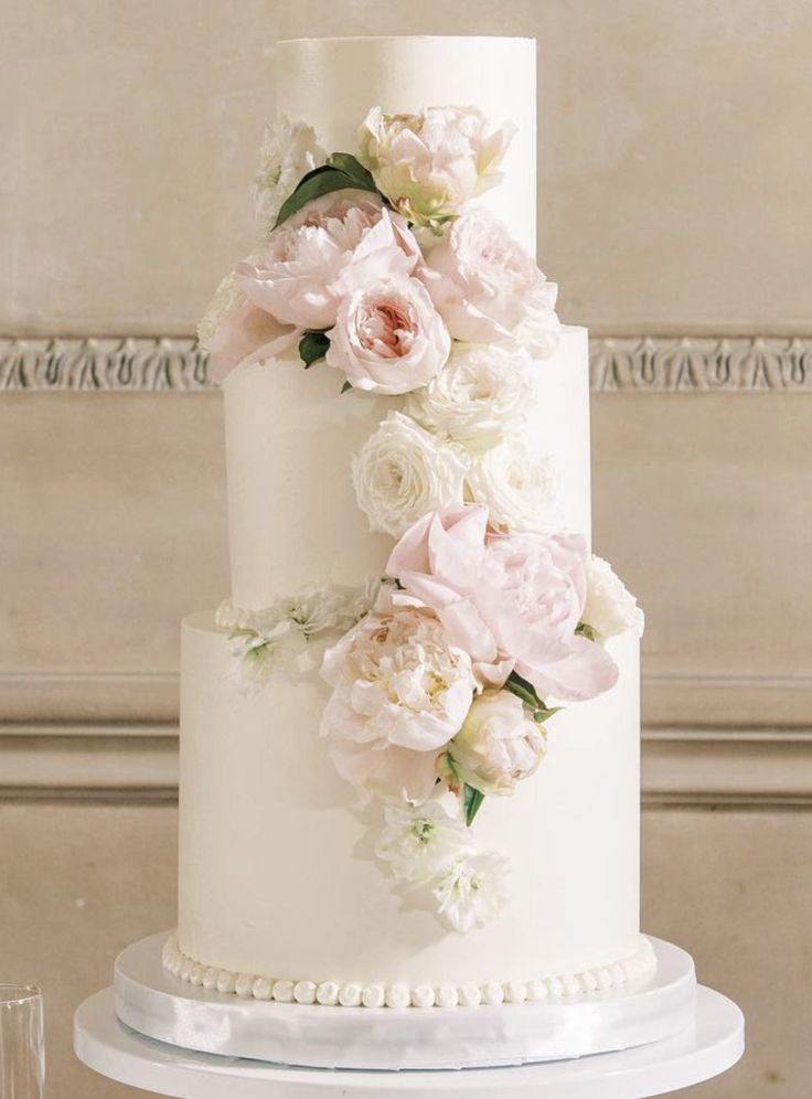 a white wedding cake with pink flowers and pearls