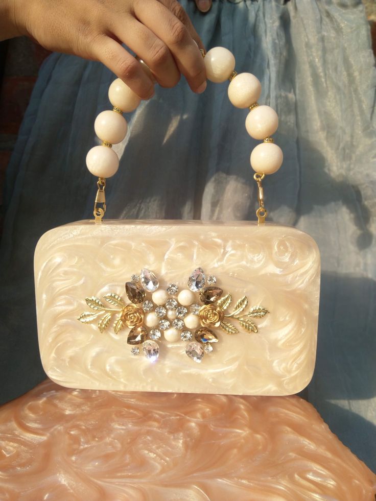 💥 Detailed Description: Elevate your accessory game with our trendy resin clutch bag, featuring an exquisite beaded handle and stunning pearl diamond embellishments. This handcrafted piece is perfect for making a bold statement at weddings, parties, and special occasions. Each clutch is meticulously crafted with high-quality resin and adorned with intricate beadwork and faux pearls, ensuring a unique and luxurious accessory. 💥 Product Details ● Handmade item ● Materials: High-quality Resin, Be Cream Rectangular Box Bag For Gifts, Rectangular Cream Box Bag For Gift, Rectangular Cream Box Bag For Gifts, Luxury Handheld Box Bag For Gift, Luxury Handheld Box Bag As Gift, Handheld Beige Box Bag For Gifts, Handheld Box Bag With Pearl Handle For Gifts, Handheld Box Bag With Pearl Handle As Gift, Handheld Box Bag With Pearl Handle