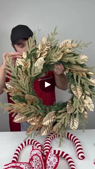 a woman is making a christmas wreath with candy canes and greenery on the table