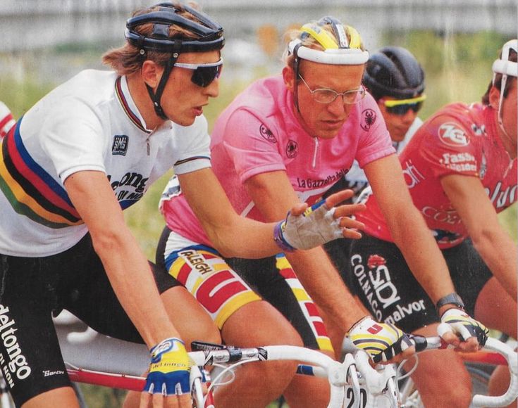 three men riding bikes on a road with helmets and gloves around their necks, one man is looking at his cell phone