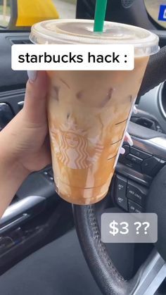 someone is holding up a starbucks drink in their car