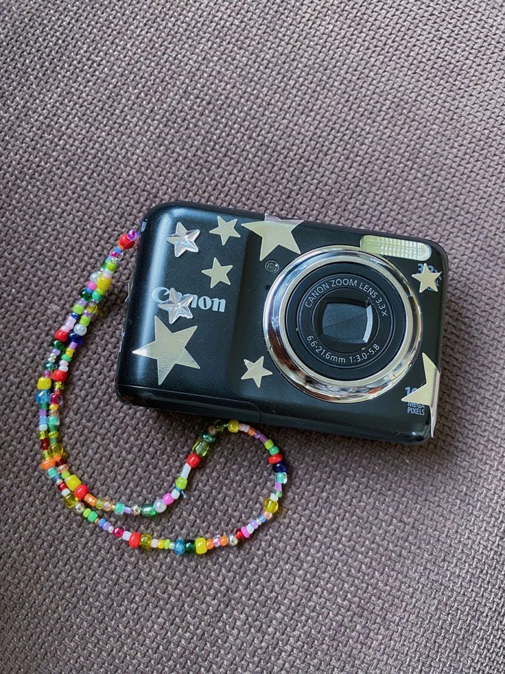 a black camera with white stars on it and a colorful beaded lanyard around the strap