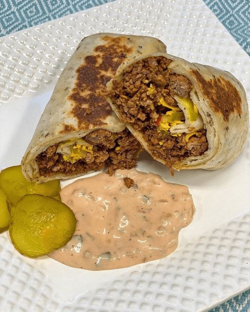 a burrito and pickles on a white plate