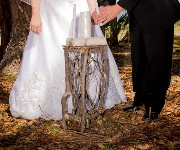 a bride and groom are holding hands over a small table made out of tree branches