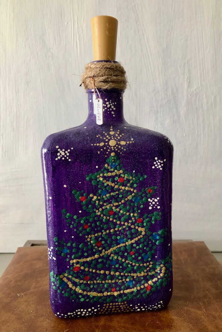 a purple bottle with a christmas tree painted on it