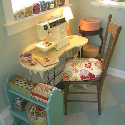 a sewing machine sitting on top of a table next to a chair and shelf filled with items