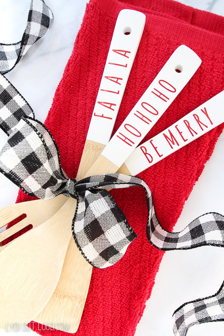 three wooden spatulas tied to a red towel with black and white checkered ribbon