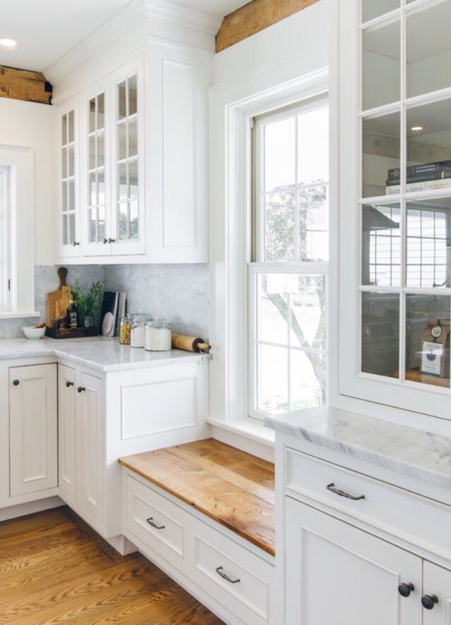 a kitchen with white cabinets and wood floors