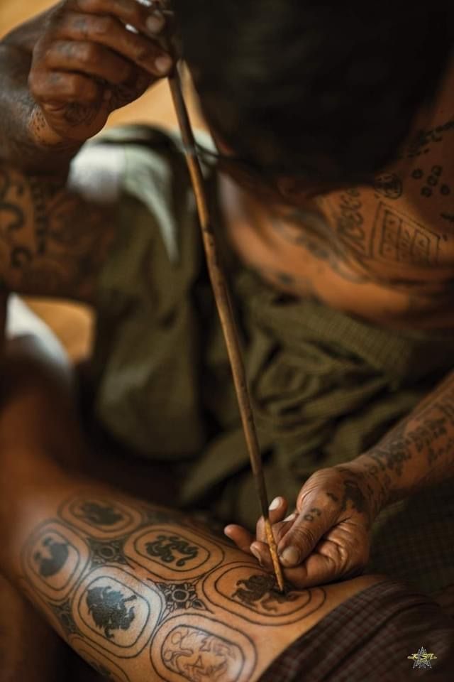 a man with tattoos on his body is holding a stick