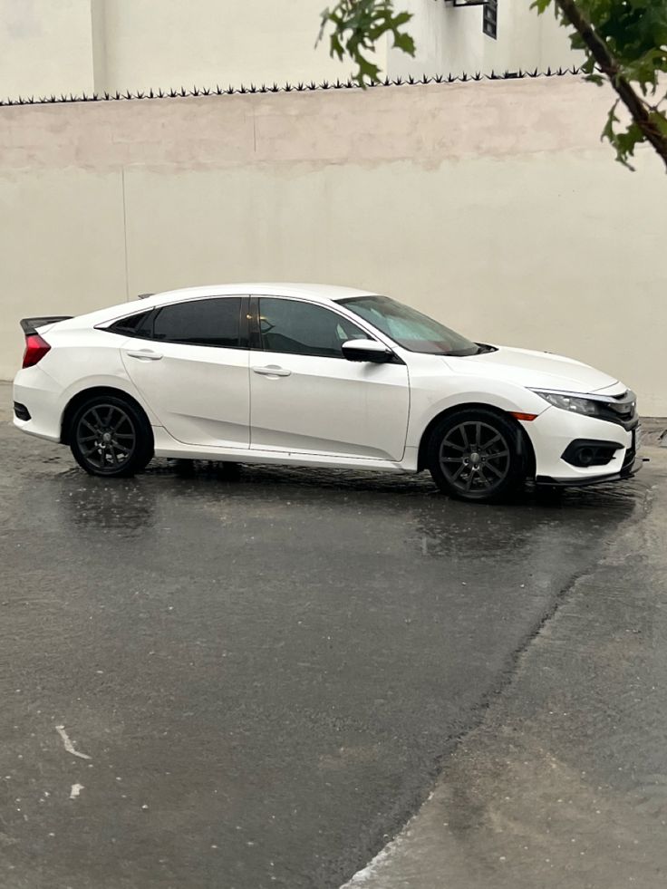 a white car parked in front of a building on a wet parking lot with no one around