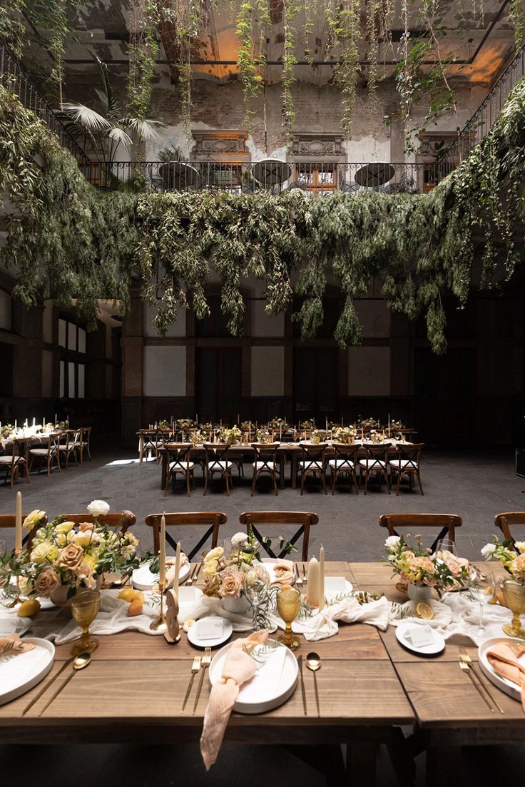 a long table set up with plates and place settings for an outdoor dinner in the middle of a building