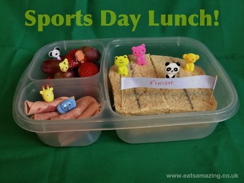 a plastic container filled with food on top of a green tablecloth covered table next to a sign that says sports day lunch