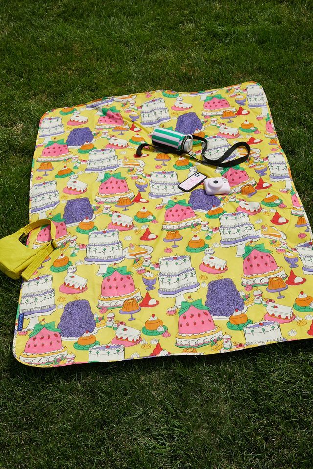 a yellow picnic blanket with scissors and other items on it sitting in the green grass