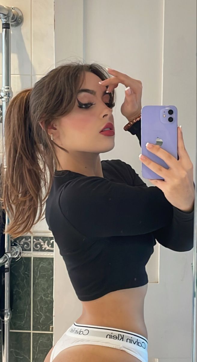 a woman taking a selfie in front of a bathroom mirror with her cell phone