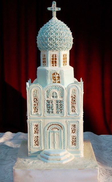 a large white cake with a church on it's side and a cross at the top