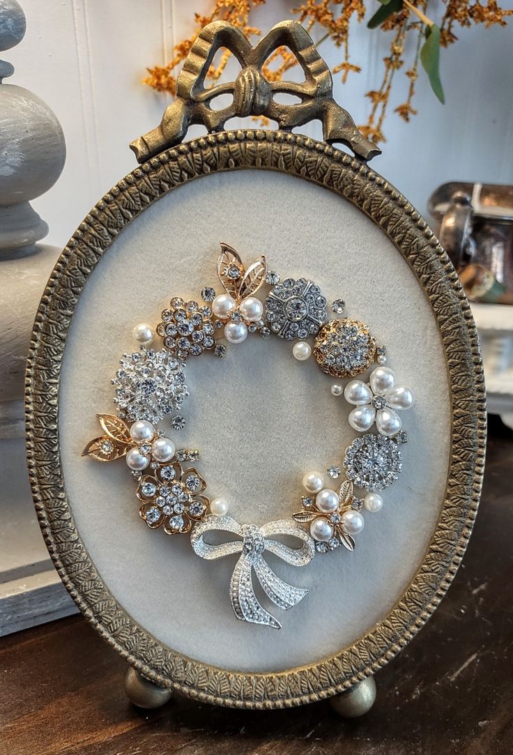 a close up of a wreath with pearls and brooches on a wooden table