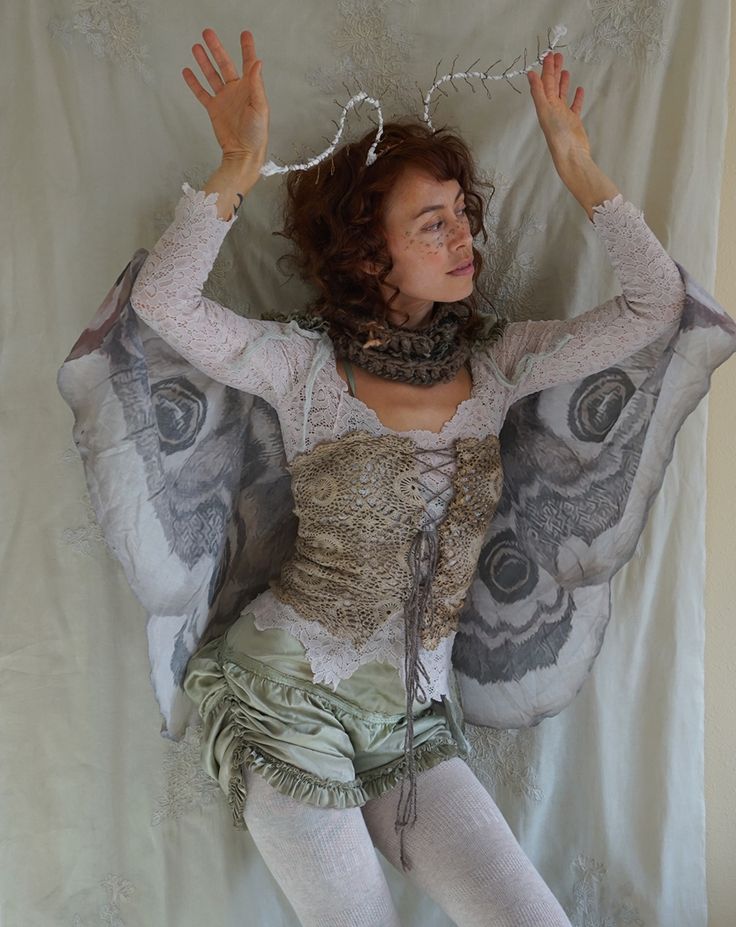 a woman laying on top of a bed with her hands in the air and wearing a costume