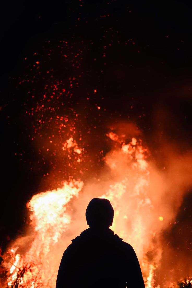 a man standing in front of a large fire