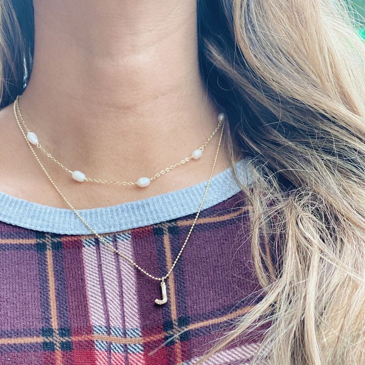 a close up of a woman wearing a plaid shirt with a necklace on her neck