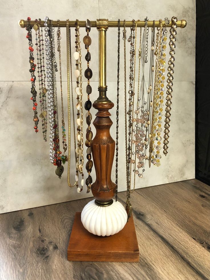 a wooden stand with beads and necklaces hanging from it's sides on a wood floor