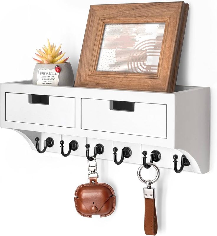 a white shelf with two key hooks and a leather purse hanging from it's side