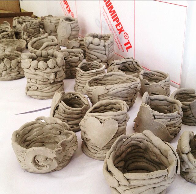 many clay pots are on the table with white cloths and red tape around them