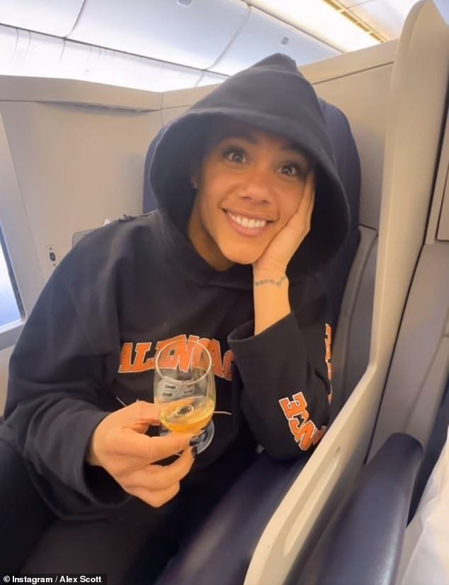 a woman sitting on an airplane holding a drink