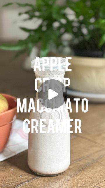 an apple cider is sitting on a table next to some bowls with apples in them