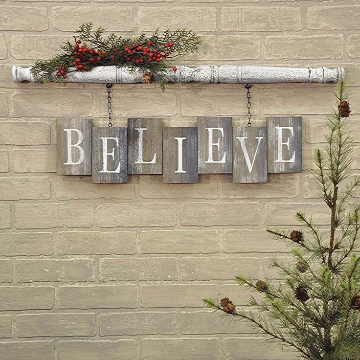 a brick wall with three wooden signs hanging from it's sides and a pine tree in the foreground